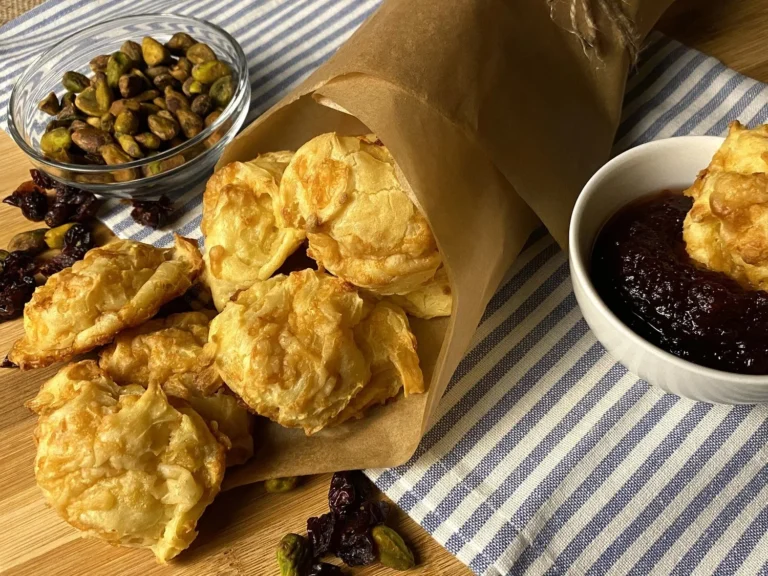 Gougères au fromage dorées et aériennes sur une assiette en bois.