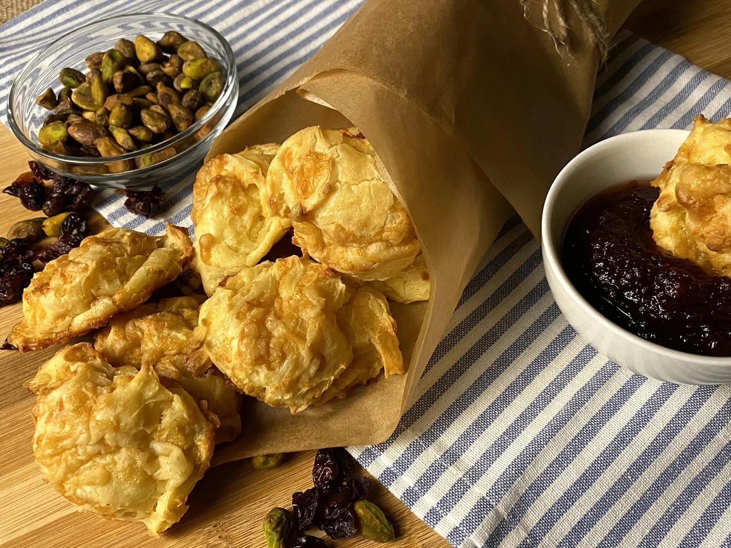 Gougères au fromage dorées et aériennes sur une assiette en bois.