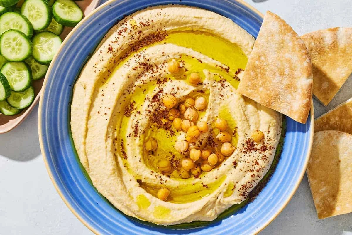 Hummus Méditerranéen crémeux servi avec des légumes frais et du pain pita