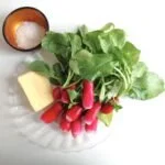 Radis au Beurre préparés avec du beurre frais sur une planche à découper.